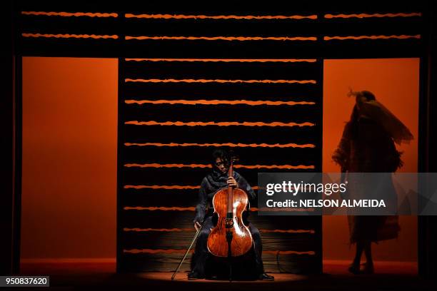 Musician plays the cello, as a model presents a creation by designer Fernanda Yamamoto, during the Sao Paulo Fashion Week in Sao Paulo, Brazil on...