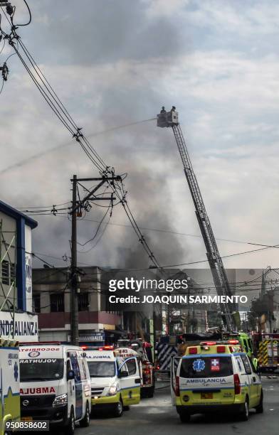 Firefighters work to extinguish a fire at a paint warehouse in Alpujarra district, in Medellin, Colombia on April 24, 2018