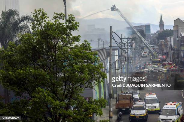 Firefighters work to extinguish a fire at a paint warehouse in Alpujarra district, in Medellin, Colombia on April 24, 2018