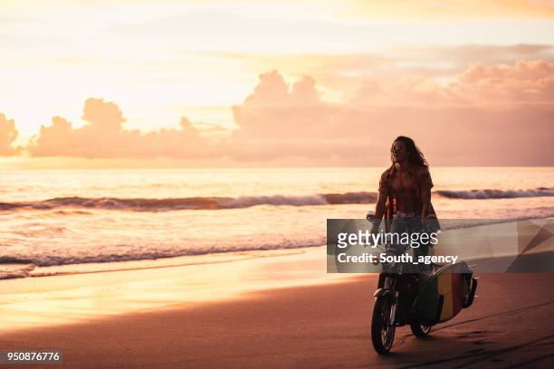 giovane in moto al tramonto - mare moto foto e immagini stock