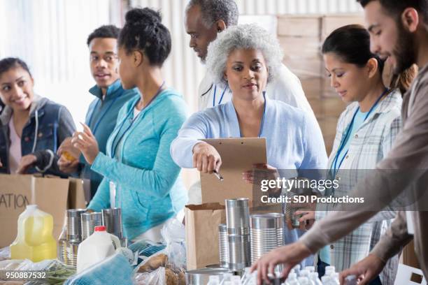 food bank manager instructing volunteers - homeless shelter man stock pictures, royalty-free photos & images