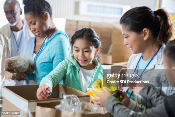 young girl and her mom volunteer during food drive - food donation stock pictures, royalty-free photos & images