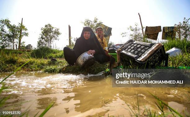 Woman washes pots and utensils in a stream of water in the village of Sayyed Dakhil, to the east of Nasariyah city some 300 kilometres south of...