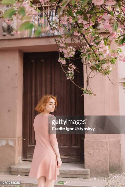 young woman standing against closed door - female looking away from camera serious thinking outside natural stock pictures, royalty-free photos & images