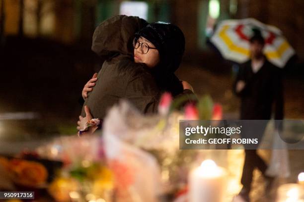 Mourners share a hug during a candle light vigil near the site of the deadly van attack, April 24, 2018 in Toronto, Ontario. - A van driver who ran...