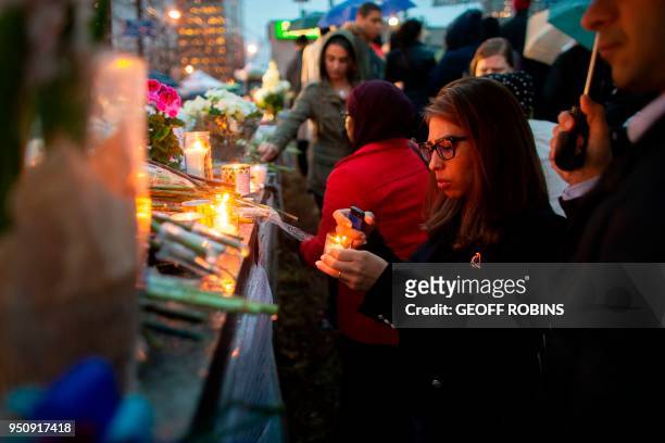 Woman lights a candle during a vigil near the site of the deadly van attack, April 24, 2018 in Toronto, Ontario. - A van driver who ran over 10...
