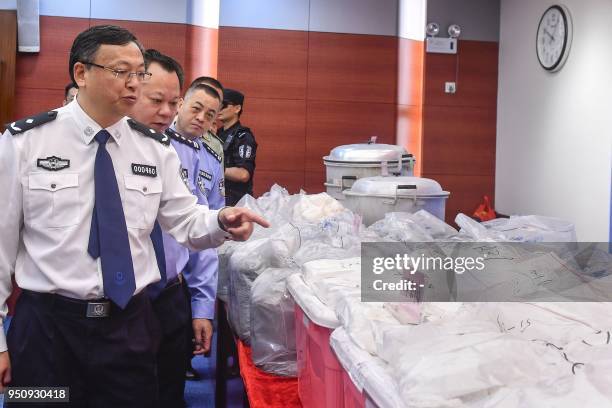 This photo taken on April 24, 2018 shows police officers looking at bags of cocaine seized in Guangzhou in China's southern Guangdong province. -...