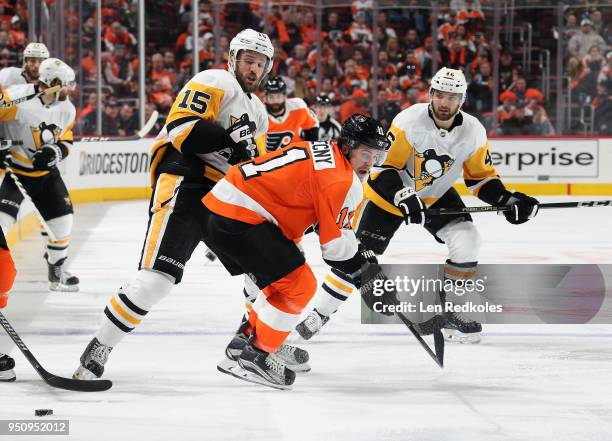 Travis Konecny of the Philadelphia Flyers reacts to the puck against Riley Sheahan and Zach Aston-Reese of the Pittsburgh Penguins in Game Four of...