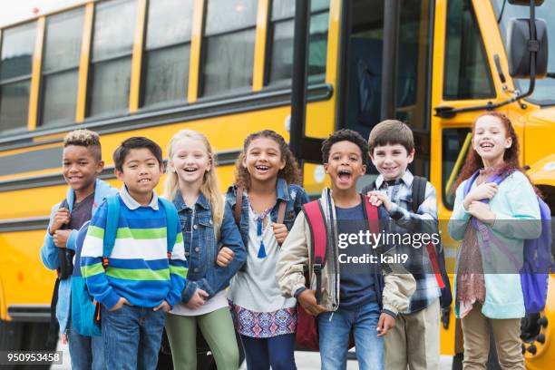 grundschulkinder warten draußen bus - schulrucksack stock-fotos und bilder