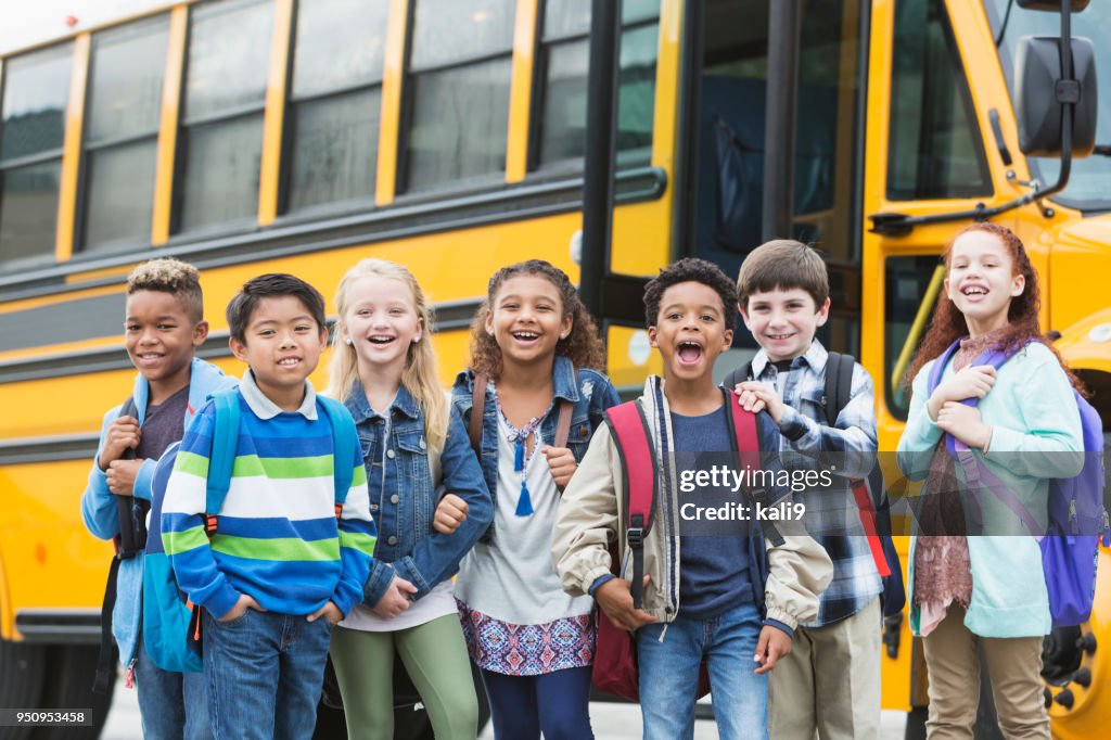 Elementary school children waiting outside bus