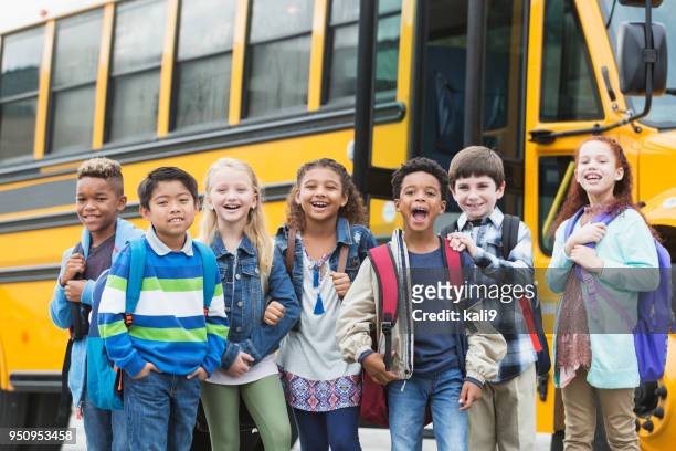 elementary school children waiting outside bus - child rucksack stock pictures, royalty-free photos & images