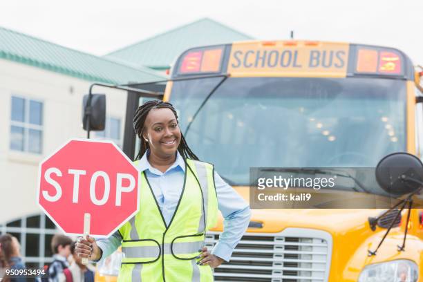 一時停止の標識を保持している学校のバスの前でガードを渡る - 交通誘導員 ストックフォトと画像