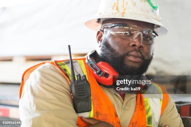 operaio afroamericano in duro cappello, gilet riflettente - earmuffs foto e immagini stock