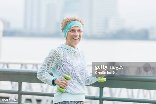 senior woman power walking on city waterfront - headband stock pictures, royalty-free photos & images