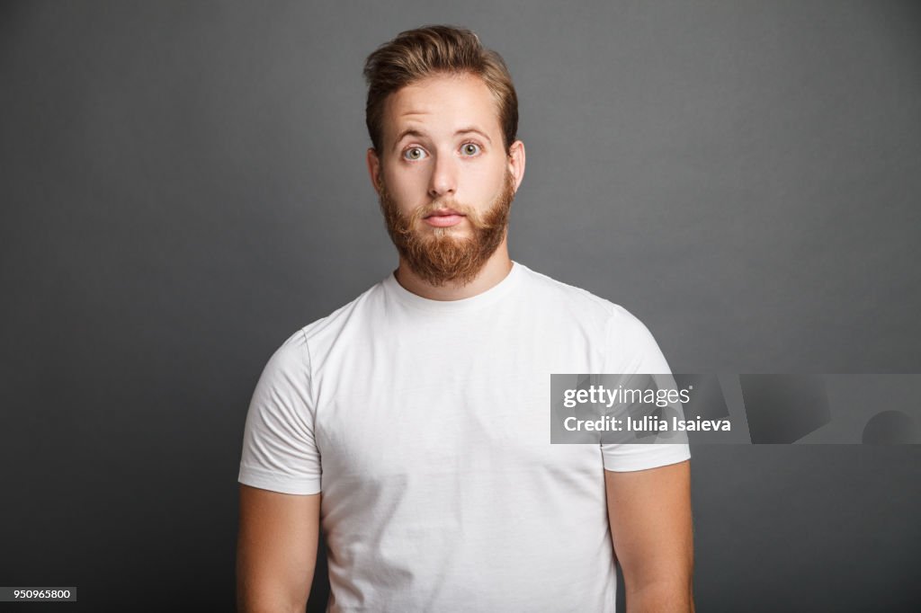 Surprised young man posing on gray