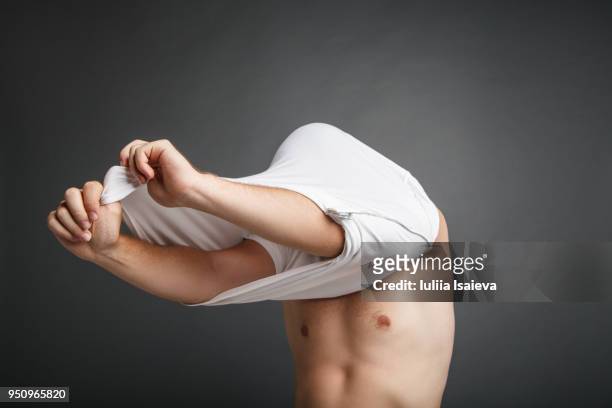 anonymous man taking off t-shirt - uitkleden stockfoto's en -beelden