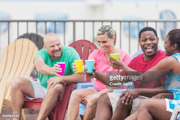 two couples hanging out on pool deck, talking, toasting - adirondack chair closeup stock pictures, royalty-free photos & images