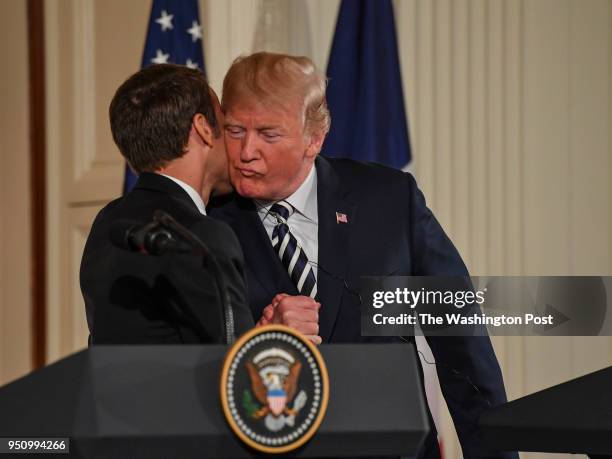 French president Emmanuel Macron kisses President Donald Trump during a joint press conference in the East Room at the White House on April 24, 2018...