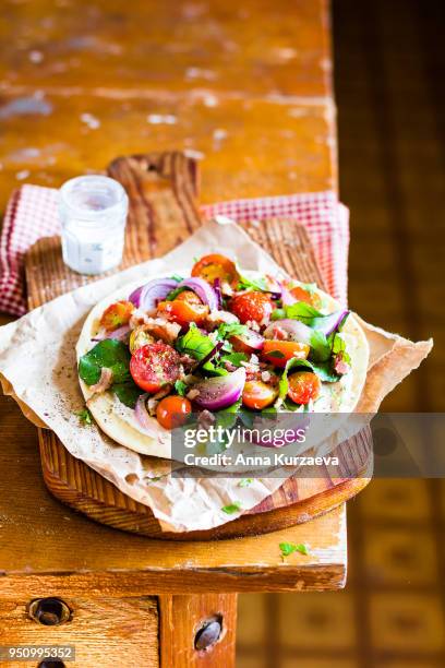 homemade wheat flat bread with fresh chard leaves, roasted cherry tomatoes, red onion and crispy bacon with cream cheese sauce on a wooden cutting board for a snack for picnic, selective focus - roasted red onion fotografías e imágenes de stock