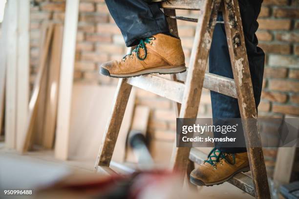 unrecognizable manual worker moving up the ladders at construction site. - work shoe stock pictures, royalty-free photos & images