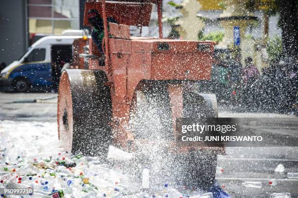 An Indonesian worker destroy bottles of bootleg alcohol after a recent raid in Surabaya on April 25, 2018. In total around 100 Indonesians are...