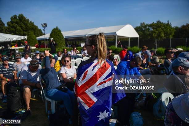 Young woman stands with the Australian national flag as people attend a ceremony marking the 103rd anniversary of ANZAC Day at Lone Pine Cemetery on...