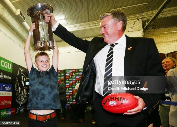 Jett Buckley, son of Magpies head coach Nathan Buckley, holds up the Anzac Trophy with Magpies President Eddie McGuire during the round five AFL...