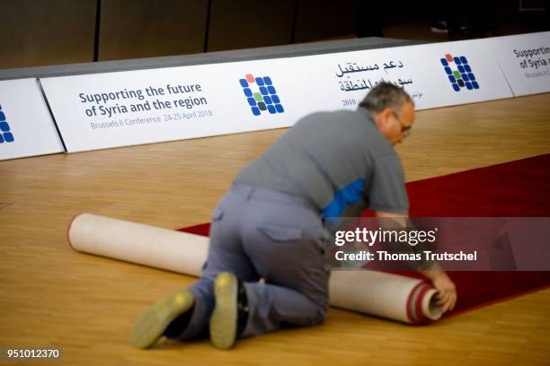 Worker rolls in a red carpet during Brussels II Conference Supporting the future of Syria and the region on April 25, 2018 in Brussels, Belgium.