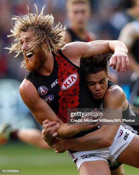 Dyson Heppell of the Bombers is tackled by Josh Thomas of the Magpies during the 2018 AFL round five ANZAC Day match between the Collingwood Magpies...