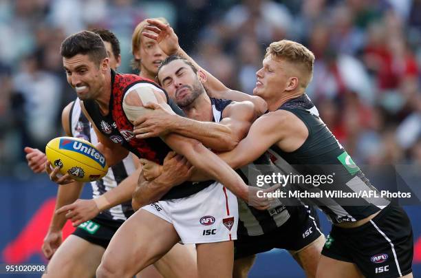 David Myers of the Bombers is tackled by Brodie Grundy and Adam Treloar of the Magpies during the 2018 AFL round five ANZAC Day match between the...