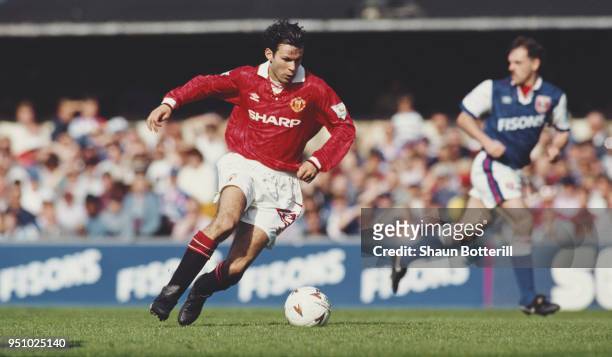 Manchester United winger Ryan Giggs on the ball as Town defender John Wark of Ipswich looks on during a Premiership match at Portman Road on May 1,...