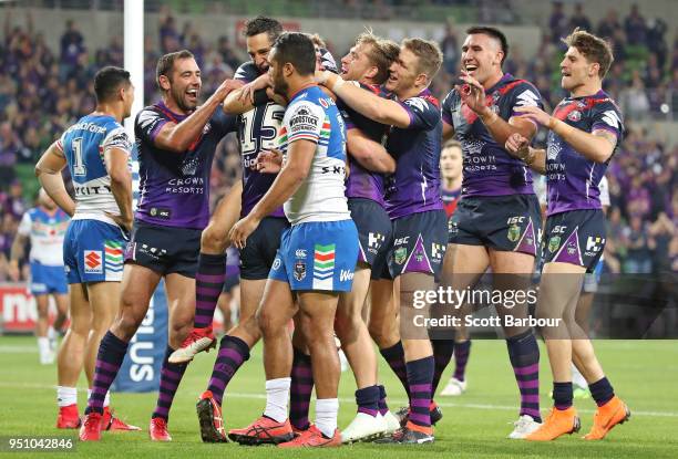 Christian Welch of the Melbourne Storm is congratulated by Billy Slater of the Melbourne Storm and his teammates after scoring a try as Peta Hiku of...