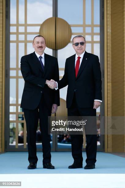 In this handout photo provided by The Turkish President Press office, Turkish President Recep Tayyip Erdogan shake hands with Ilham Aliyev, President...