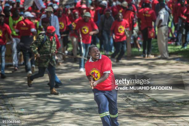 Demonstrator wearing a t-shirt of the National Union of Metalworkers of South Africa runs with a stick as thousands of workers take part in a...