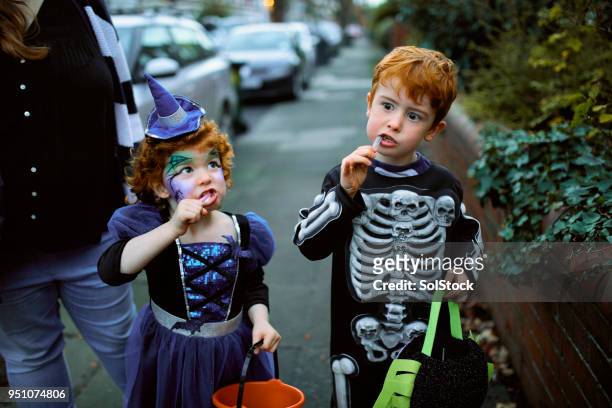 frères et sœurs, manger des bonbons d’halloween - street party stock photos et images de collection