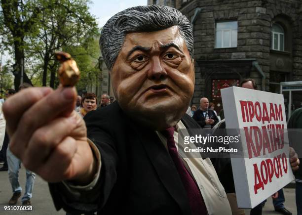 Man carries a costume depicting President Petro Poroshenko saddling average Ukrainian citizen and carrying a placard &quot;The country for sale&quot;...