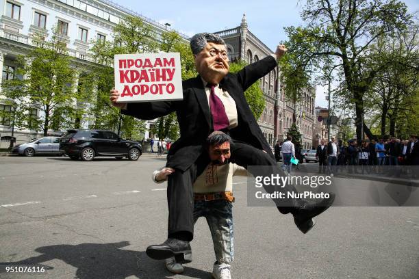 Man carries a costume depicting President Petro Poroshenko saddling average Ukrainian citizen and carrying a placard &quot;The country for sale&quot;...