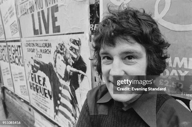 Scottish rock and blues musician Alex Harvey with a poster of one of his concerts at the London Palladium, London, UK, 28th February 1978.