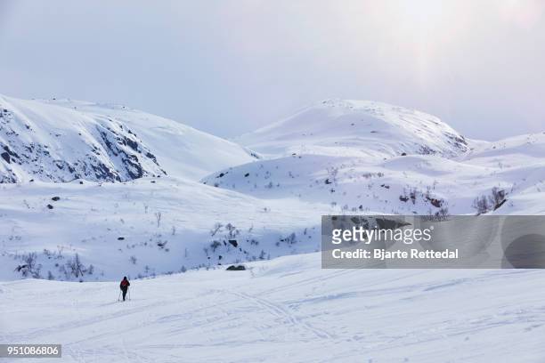 woman cross-country skiing through mountain landscape - bjarte rettedal stock-fotos und bilder