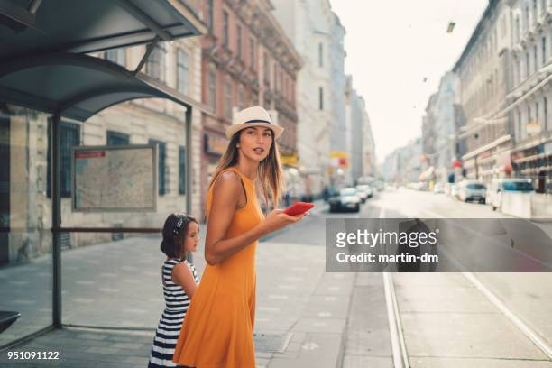 madre con figlia alla fermata dell'autobus - aspettare foto e immagini stock
