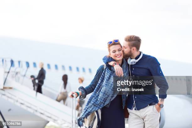 romantic couple arriving at their travel destination - couple airplane stock pictures, royalty-free photos & images