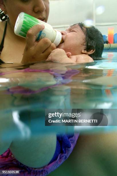 Fernanda Herrera feeds her daughter Betty, 3 months, during a swimming class in Quito, 20 March 2002. Fernanda Herrera alimenta a su hija Betty, de 3...