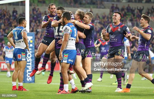 Christian Welch of the Melbourne Storm is congratulated by Billy Slater of the Melbourne Storm and his teammates after scoring a try as Peta Hiku and...