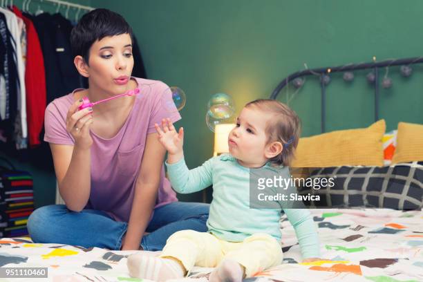 mother and daughter blowing soap bubbles - catching bubbles stock pictures, royalty-free photos & images