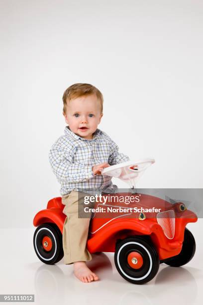 baby boy riding on toy car - bobbycar stockfoto's en -beelden