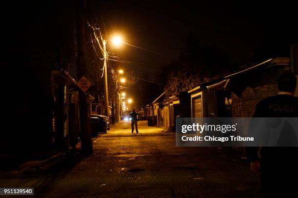 Police search an alley at the scene where two people were shot near the intersection of 60th and Maplewood Avenue Tuesday April 24, 2018 in Chicago.