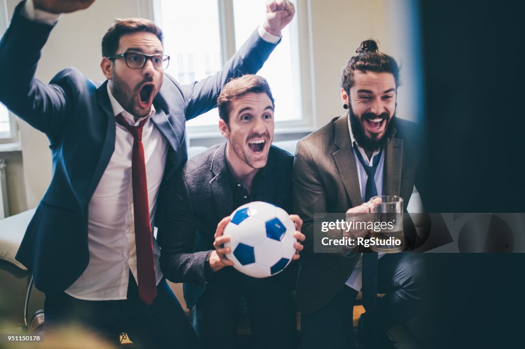 Homens de negócios alegre apoiar as suas equipas de futebol favorito na emoção