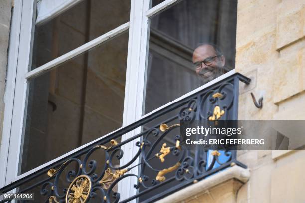 French Prime Minister Edouard Philippe smiles looking from a window at the Hotel de Matignon on April 25, 2018 in Paris, after a meeting with the...