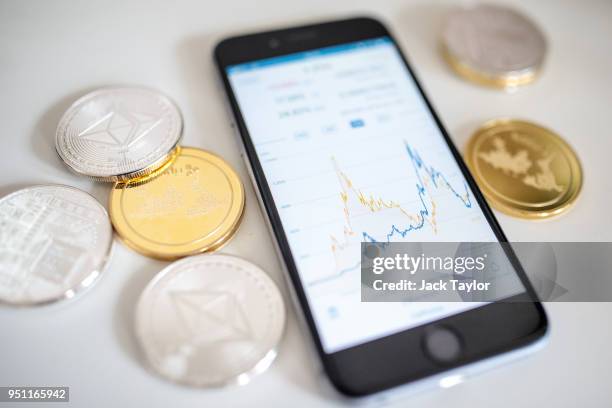 In this photo illustration of the litecoin, ripple and ethereum cryptocurrency 'altcoins' sit arranged for a photograph beside a smartphone...