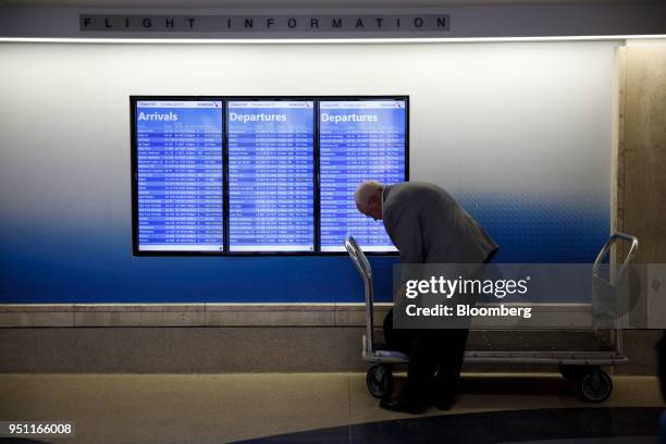 Traveler stands in front of an American Airlines Group Inc. Departures board at Los Angeles International Airport in Los Angeles, California, U.S.,...